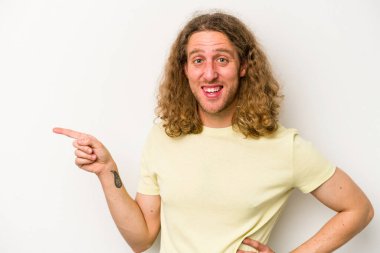 Beyaz arka planda izole edilmiş genç beyaz adam işaret parmağıyla işaret ederek gülümsüyor..