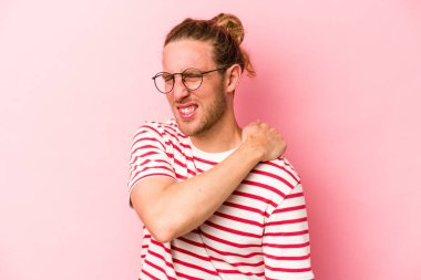 Pembe arka planda izole edilmiş, omuz ağrısı olan genç beyaz bir adam..
