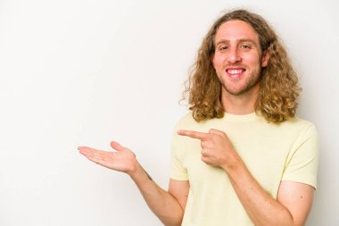 Beyaz arka planda izole edilmiş genç beyaz bir adam, palmiye üzerinde bir fotokopi alanı tutarken heyecanlı..