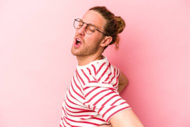 Pembe arka planda izole edilmiş beyaz bir adam sırt ağrısı çekiyor..