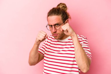 Pembe arka planda izole edilmiş genç beyaz bir adam bir tartışma yüzünden yumruk, öfke, kavga ve boks atıyor..