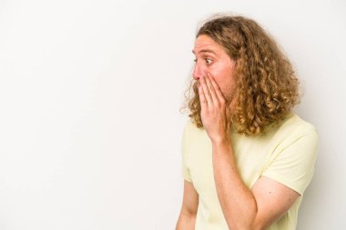 Beyaz arka planda izole edilmiş genç beyaz adam gördüğü bir şey yüzünden şoka uğruyor..