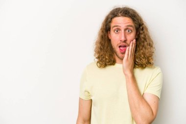 Beyaz arka planda izole genç beyaz adam yüksek sesle bağırıyor, gözleri açık ve elleri gergin tutuyor..