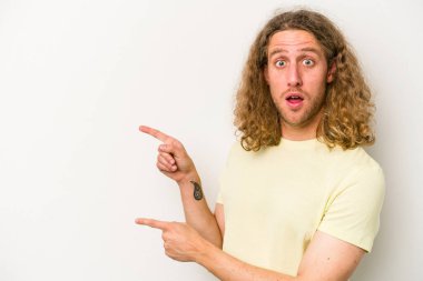 Beyaz arka planda izole edilmiş genç beyaz bir adam işaret parmağıyla fotokopi alanını işaret ederek heyecan ve arzusunu ifade ediyor..