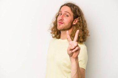 Beyaz arka planda izole edilmiş genç beyaz bir adam zafer işareti gösteriyor ve gülümsüyor..