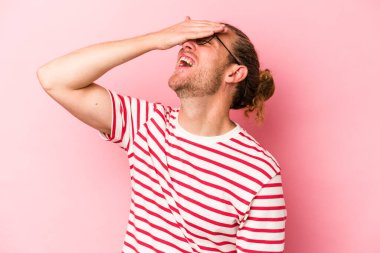 Pembe arka planda izole edilmiş genç beyaz adam ellerini başının üstünde tutarak neşeyle gülüyor. Mutluluk kavramı.