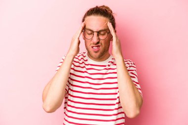 Pembe arka planda izole edilmiş genç beyaz adam tapınaklara dokunuyor ve baş ağrısı çekiyor..