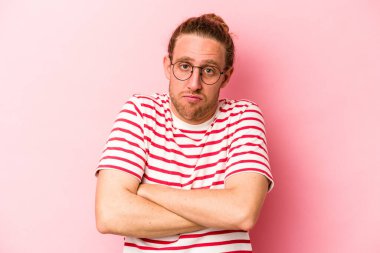 Pembe arka planda izole edilmiş genç beyaz adam omuzlarını silkeliyor ve gözleri açık..