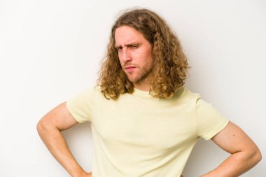 Beyaz arka planda izole edilmiş, hoşnutsuzca kaşlarını çatmış, kollarını kavuşturmuş genç beyaz bir adam..