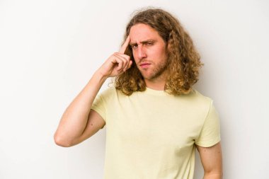 Beyaz arka planda izole edilmiş genç beyaz bir adam şakağı parmağıyla işaret ediyor, düşünüyor ve bir göreve odaklanıyor..