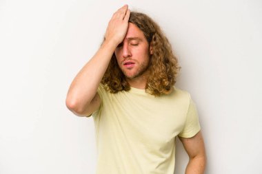 Beyaz arka planda izole edilmiş genç beyaz bir adam bir şeyi unutuyor. Alnına avuç içi ve gözlerini kapayarak vuruyor..