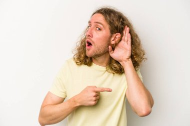 Beyaz arka planda izole edilmiş genç beyaz adam bir dedikoduyu dinlemeye çalışıyor..