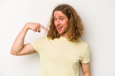 Beyaz arka planda yaşayan beyaz tenli genç bir adam gömlek fotokopi alanını gösteriyor, gururlu ve kendinden emin.