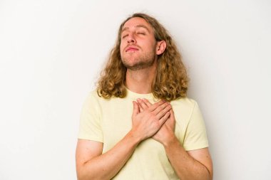 Beyaz arka planda izole edilmiş beyaz tenli genç bir adam, dostane bir ifadeye sahip, avuçlarını göğsüne bastırıyor. Aşk konsepti.