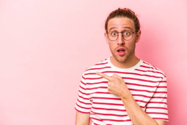 Pembe arka planda izole edilmiş genç beyaz adam yan tarafı gösteriyor.