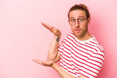 Pembe arka planda izole edilmiş genç beyaz adam elleri arasında bir fotokopi alanı tutuyor..