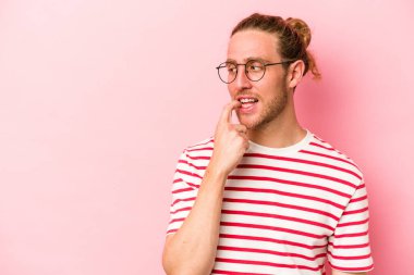 Pembe arka planda izole edilmiş genç beyaz adam rahatlamış bir şeyin fotokopi odasına baktığını düşünüyor..