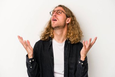 Beyaz arka planda izole edilmiş genç beyaz adam gökyüzüne haykırıyor, yukarı bakıyor, hayal kırıklığına uğramış..