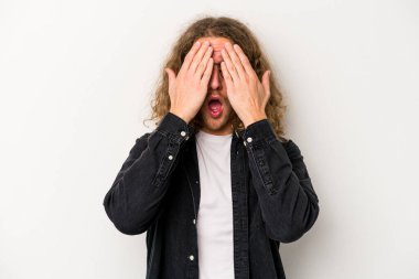 Beyaz arka planda izole edilmiş genç beyaz bir adam yüzünün yarısını palmiye ile örterek eğleniyor..