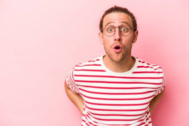 Pembe arka planda izole edilmiş genç beyaz adam gördüğü bir şey yüzünden şoka uğruyor..
