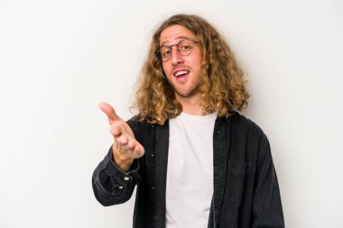 Beyaz arka planda izole edilmiş genç beyaz bir adam selamlama jesti olarak kameraya elini uzatıyor..