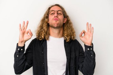 Beyaz arka planda izole edilmiş genç beyaz adam yoğun bir günün ardından rahatlıyor. Yoga yapıyor..