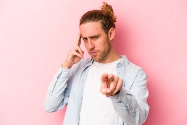 Pembe arka planda izole edilmiş genç beyaz bir adam parmağıyla tapınağı işaret ediyor, düşünüyor ve bir göreve odaklanıyor..