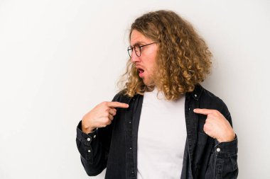 Beyaz arka planda izole edilmiş genç beyaz bir adam parmağını göstererek şaşırdı, geniş bir gülümsemeyle..