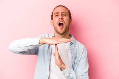 Pembe arka planda izole edilmiş genç beyaz adam bir mola hareketi gösteriyor..