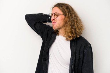 Beyaz arka planda izole edilmiş genç beyaz bir adam yorgun ve uykulu bir şekilde elini başının üstünde tutuyor..