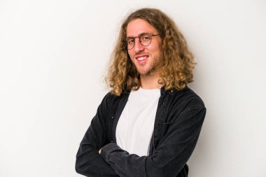 Beyaz arka planda kendini güvende hisseden, kararlılıkla kollarını kavuşturan beyaz tenli genç bir adam..