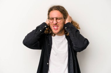 Beyaz arka planda izole edilmiş genç beyaz bir adam kulaklarını elleriyle kapatıyor..