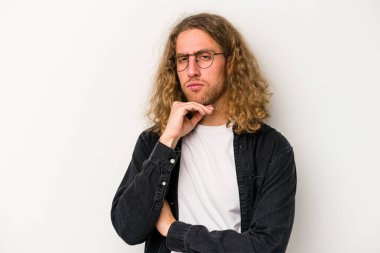 Beyaz arka planda izole edilmiş genç beyaz bir adam şüpheli, belirsiz, seni muayene ediyor..