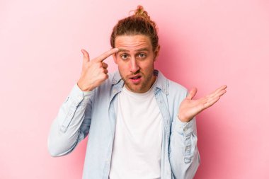Pembe arka planda izole edilmiş genç beyaz adam işaret parmağıyla hayal kırıklığı jesti gösteriyor..