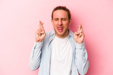 Pembe arka planda izole edilmiş beyaz bir adam şans getirsin diye dua ediyor.