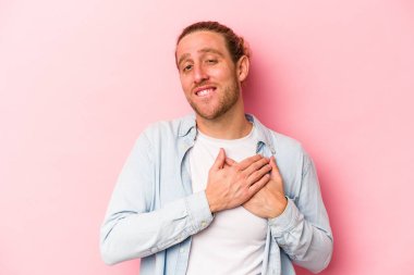 Pembe arka planda izole edilmiş genç beyaz bir adam, dostane bir ifadeye sahip, avuçlarını göğsüne bastırıyor. Aşk konsepti.