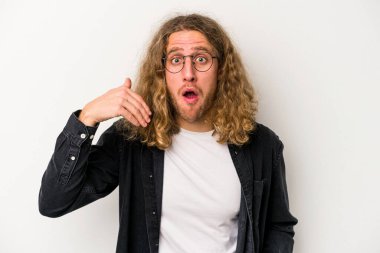 Beyaz arka planda izole olmuş genç beyaz bir adam bir şeye gülüyor, ağızlarını ellerle kapatıyor..