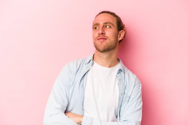 Pembe arka planda izole edilmiş genç beyaz adam hedeflere ve amaçlara ulaşma hayali kuruyor.