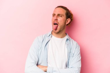 Genç, beyaz bir adam pembe arka planda izole edilmiş komik ve dost canlısı bir dil kullanıyor..