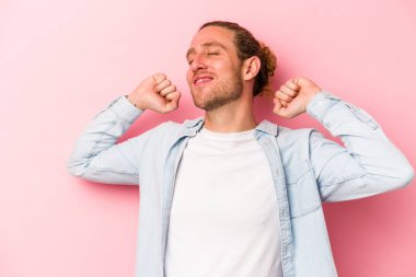 Pembe arka planda izole edilmiş genç beyaz adam kollarını uzatıyor, rahat bir konumda..