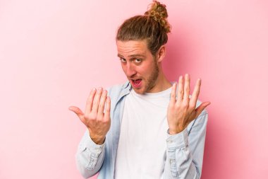 Pembe arka planda izole edilmiş genç beyaz adam sanki seni davet ediyormuş gibi seni işaret ediyor..