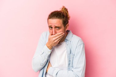 Pembe arka planda izole edilmiş genç beyaz adam korkmuş ve korkmuş..