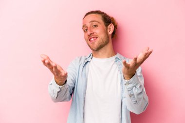 Pembe arka planda izole edilmiş genç beyaz adam hoş bir yüz ifadesi sergiliyor..