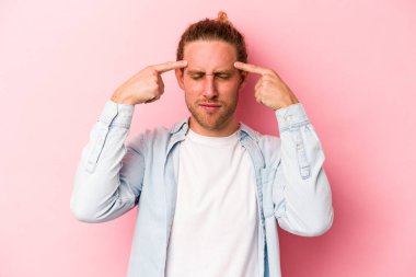 Pembe arka planda izole edilmiş genç beyaz adam bir göreve odaklanmış, parmaklarını işaret ediyor..