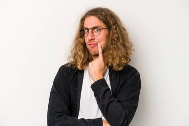 Beyaz arka planda izole edilmiş genç beyaz adam alaycı bir ifadeyle kameraya bakıyor..