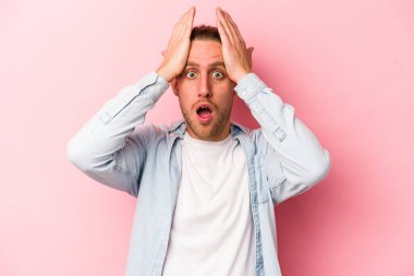 Pembe arka planda izole edilmiş genç beyaz adam şaşırdı ve şok oldu..