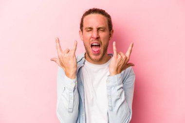 Pembe arka planda izole edilmiş genç beyaz adam boynuzlarını devrim konsepti olarak gösteriyor..
