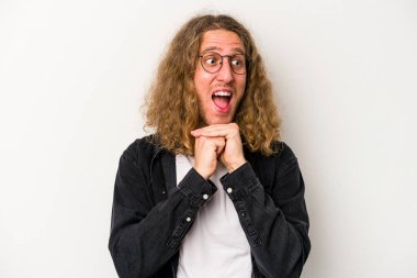 Beyaz arka planda izole genç beyaz adam ellerini çenesinin altında tutuyor, mutlu bir şekilde yana bakıyor..