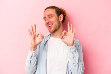Pembe arka planda izole edilmiş genç beyaz adam neşeli ve kendinden emin, iyi bir hareket gösteriyor..