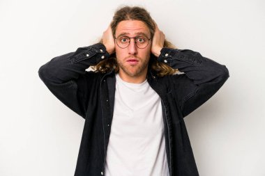 Beyaz arka planda izole edilmiş genç beyaz bir adam kulakları kulaklarıyla kapatıyor ve çok ses duymamaya çalışıyor..